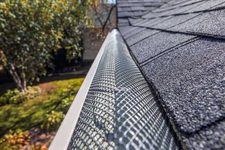 A contractor demonstrating the effectiveness of a gutter guard to a potential client in Fayetteville